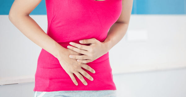 Woman in pink shirt holding stomach
