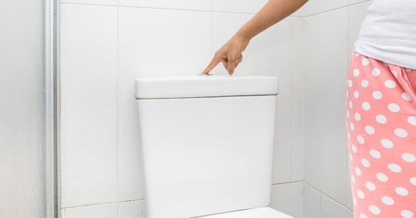 Woman in pink pajamas flushing toilet