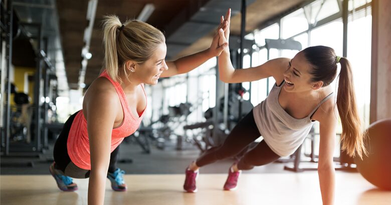 Two woman high five each other at gym